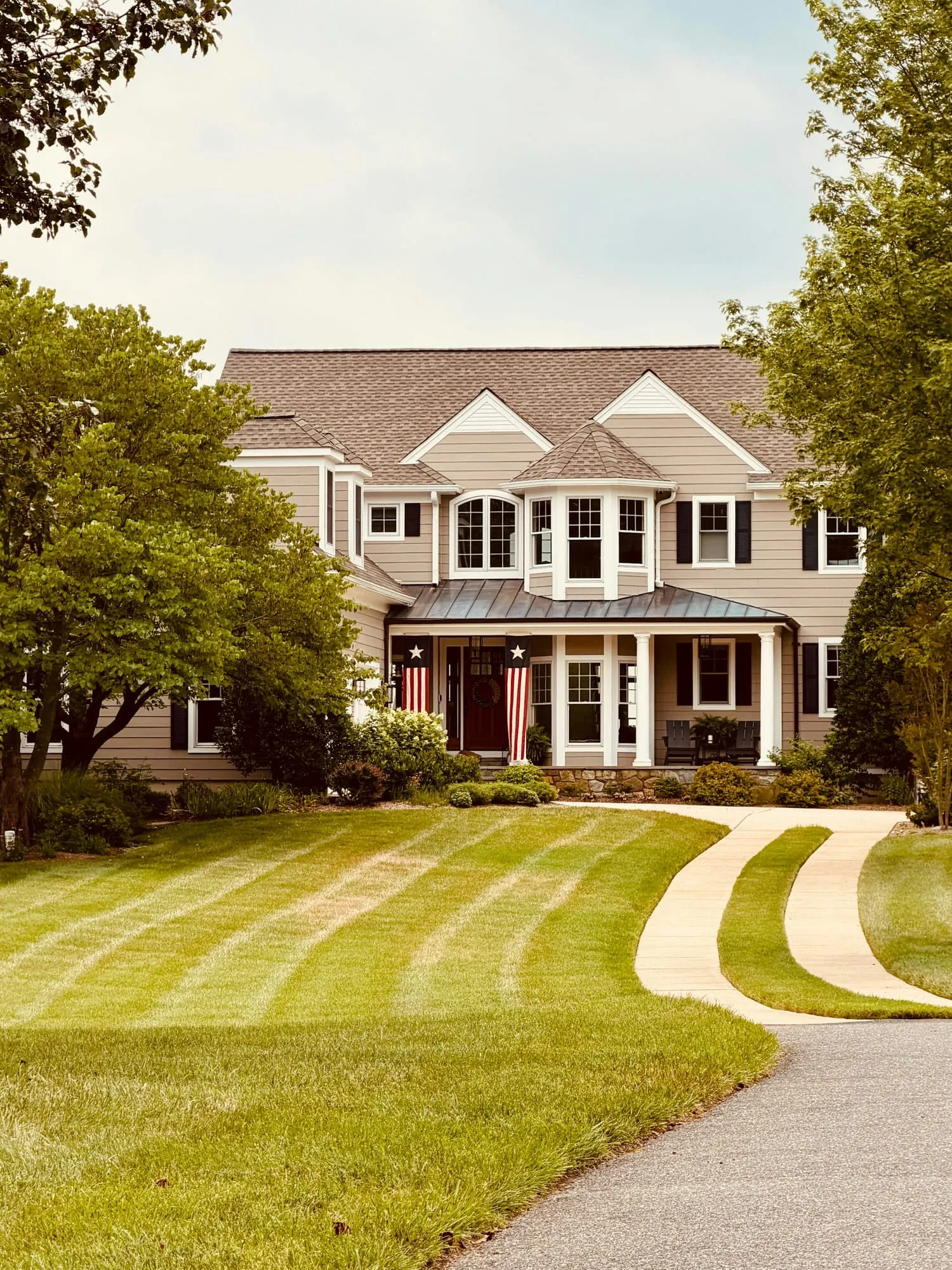 Two-story house with a freshly striped lawn and curved front path