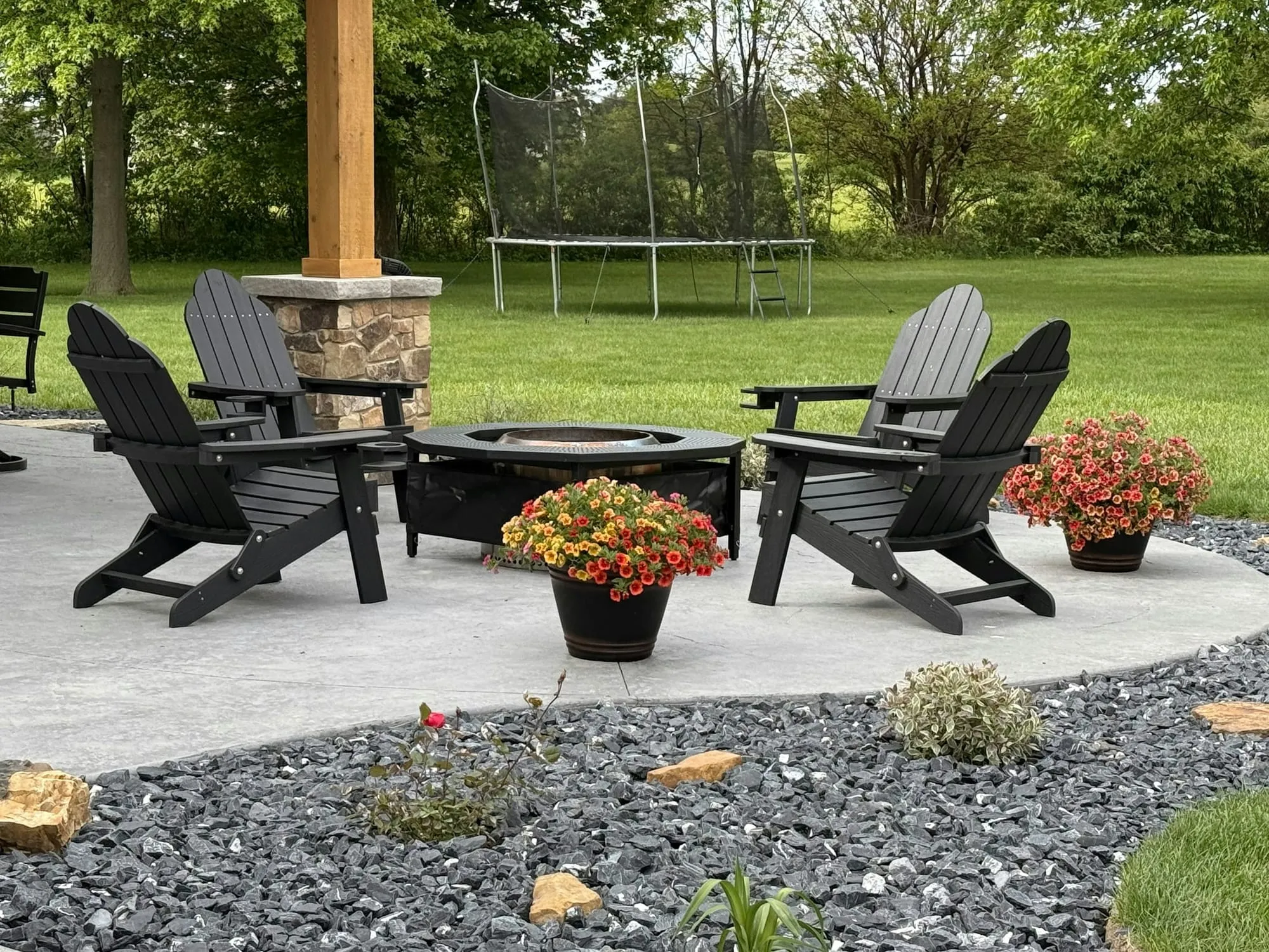 Stone patio with a fire pit and Adirondack chairs